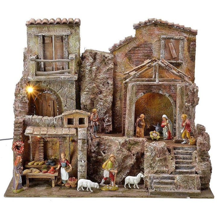 Illuminated nativity scene complete with Landi statues with houses and shops