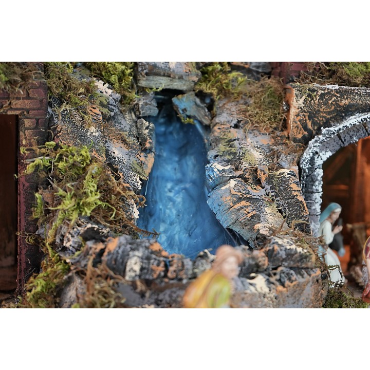 Illuminated nativity scene complete with statues with waterfall, fountain and
