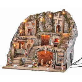 Illuminated nativity scene with statues, fountain, fire, and windmill