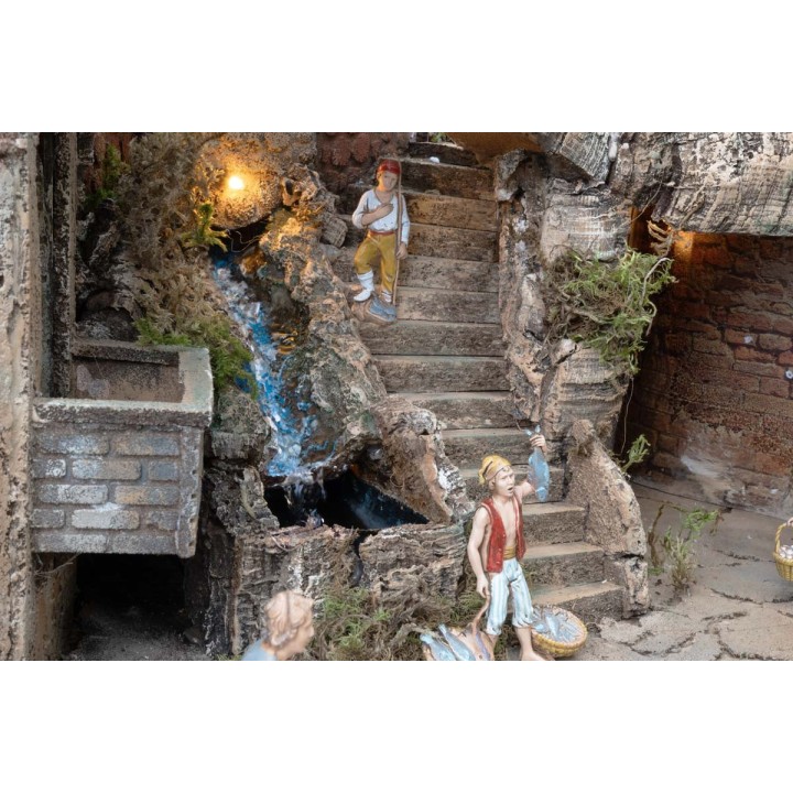 Presepe illuminato con statue, ruscello, forno e mulino a vento